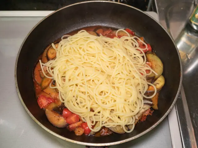 茹で上がったパスタをソースのフライパンに合わせた写真