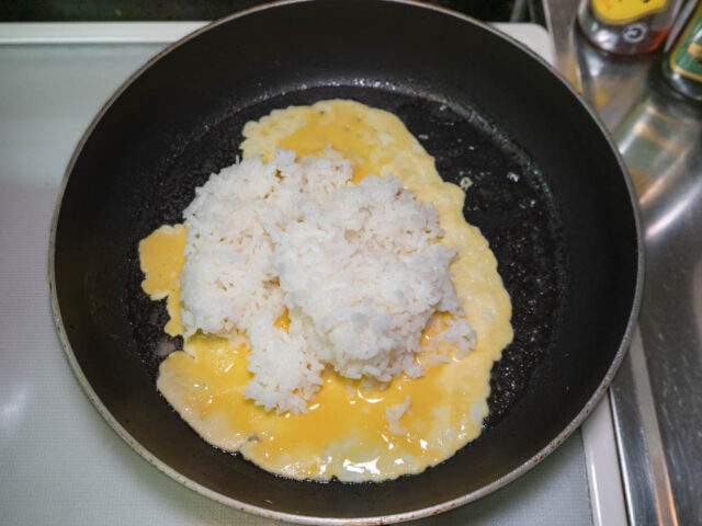 フライパンにサラダ油を熱して溶き卵とご飯を入れた写真
