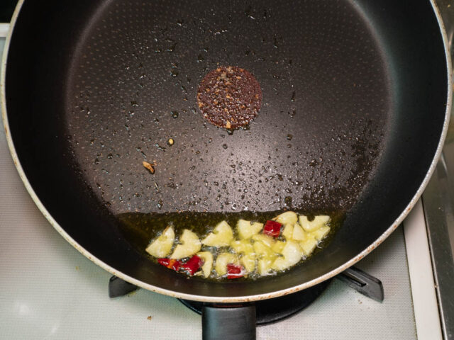 フライパンにオリーブオイル、ニンニク、唐辛子を入れて加熱する写真