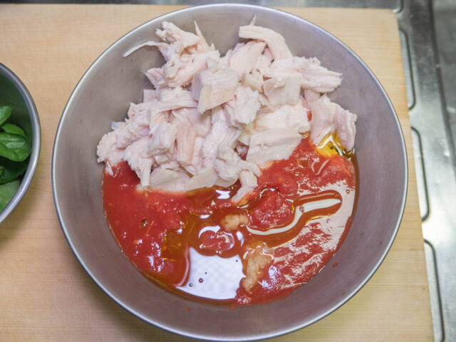 ボールにトマト缶、鶏胸肉、オリーブオイル、ニンニク、レモン果汁を加えた写真