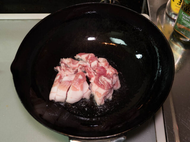 中華鍋にサラダ油を熱して豚バラ肉を入れた写真