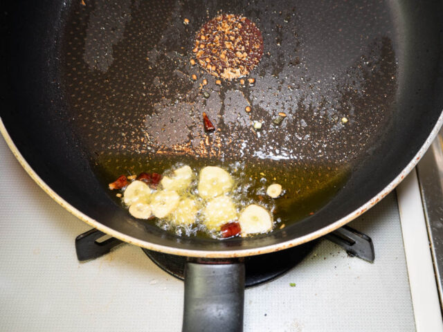 フライパンにオリーブオイル、ニンニク、唐辛子を入れて熱する写真