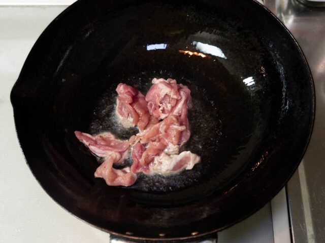 鍋にサラダ油を熱して豚肉を炒める写真