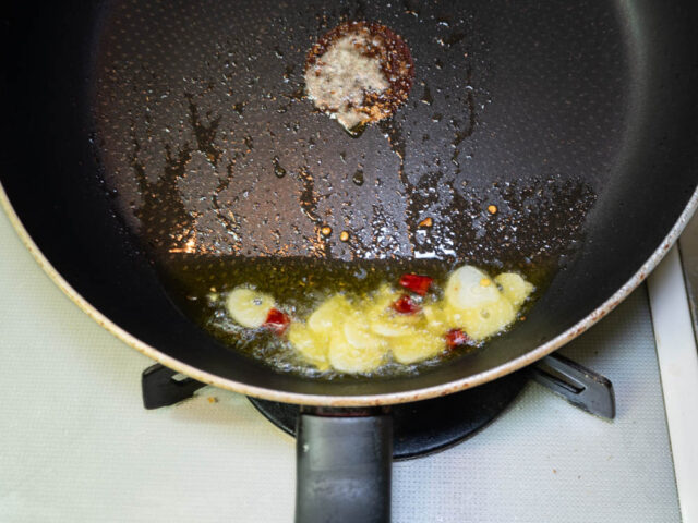 フライパンでオリーブオイル、ニンニク、唐辛子を熱する写真