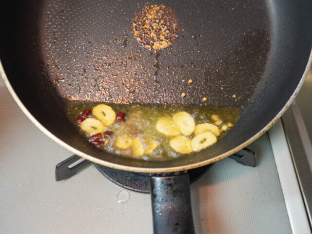 フライパンにオリーブオイル、ニンニク、唐辛子、アンチョビを入れて加熱する写真