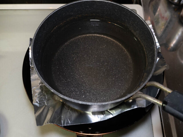 水を入れた鍋を上にのせて鶏肉を焼く写真