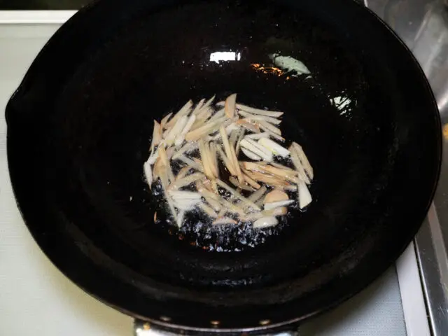 中華鍋にサラダ油を熱してニンニクと生姜を炒める写真