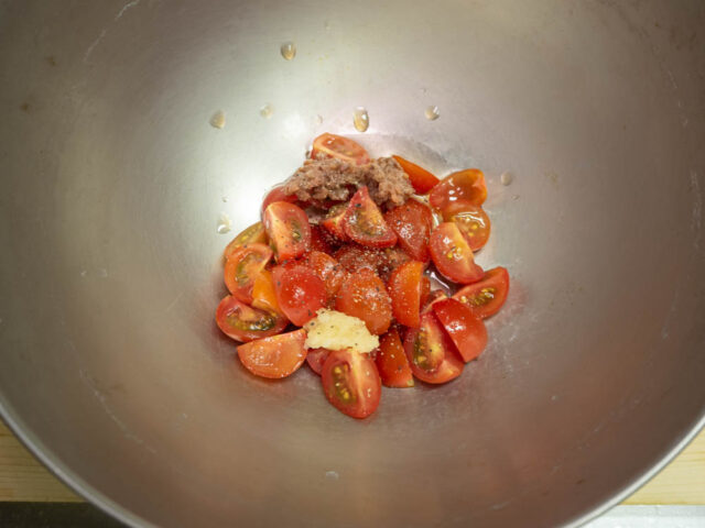 ボールにミニトマト、アンチョビ、ニンニク、胡椒を入れた写真