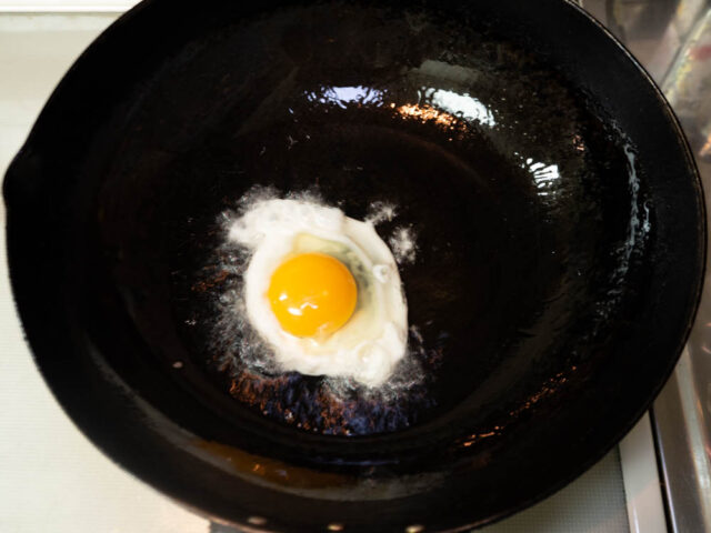 鍋に多めのサラダ油を熱して割った卵を入れた写真