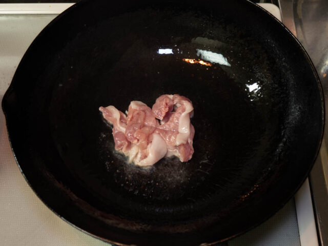 中華鍋にサラダ油を熱して豚肉を加えた写真