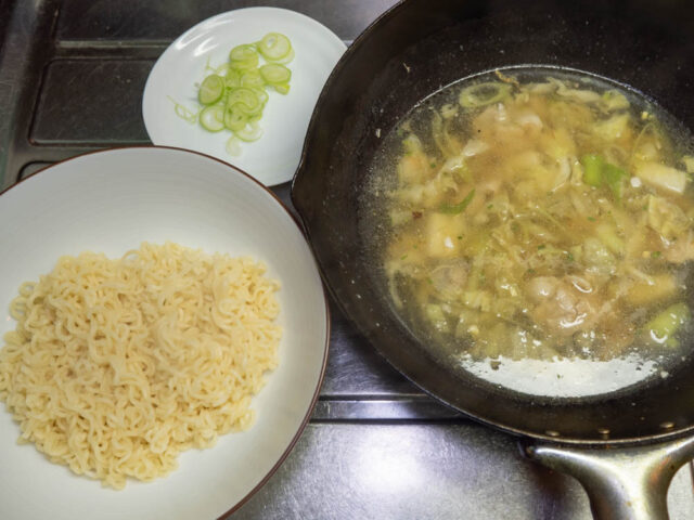 丼に入れた麺、中華鍋のスープ、小口切りにした長ねぎの写真