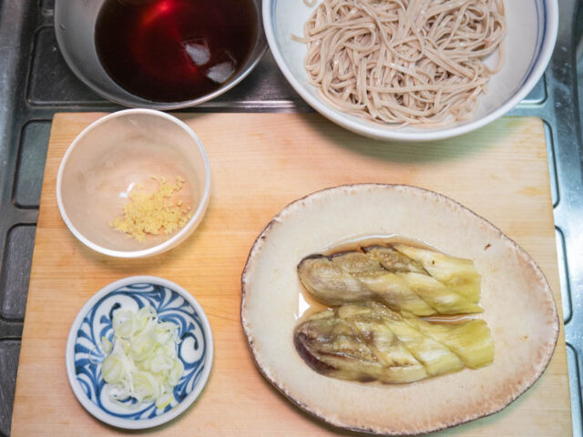 丼に入れた蕎麦、つゆ、焼き茄子、長ねぎ、生姜の写真