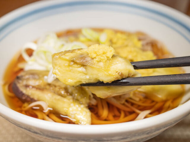 生姜をのせた焼き茄子を箸で持ち上げた写真