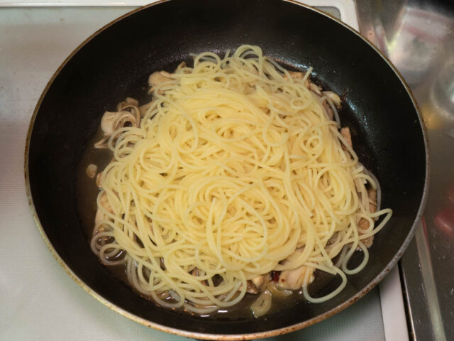 茹で上がったパスタをソースのフライパンにあわせた写真