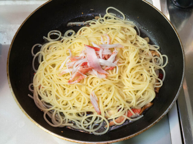 ソースのフライパンに茹でたパスタと残りのカニカマを加えた写真