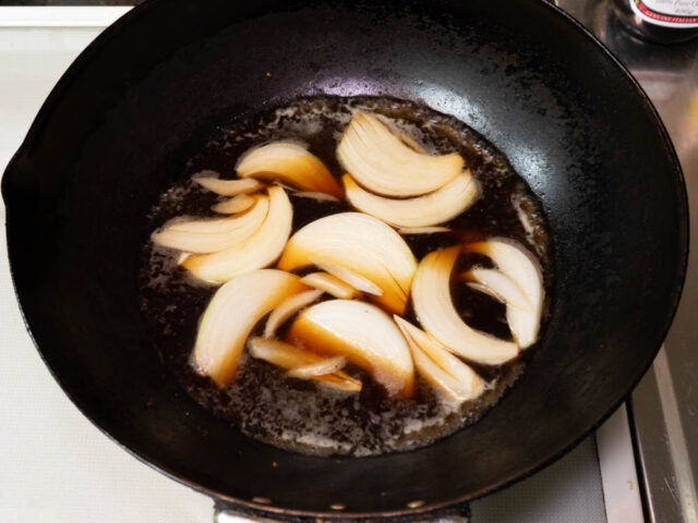 鍋に煮汁の調味料と玉ねぎを入れて火をつけた写真