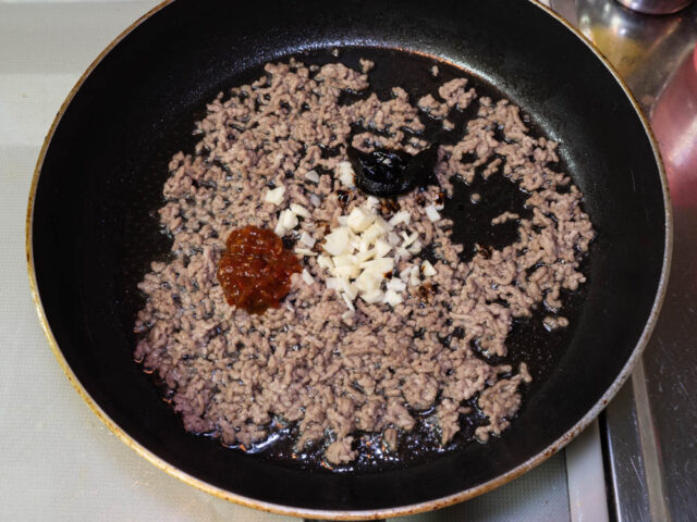 挽肉の色が変わって、豆板醤、甜麺醤、ニンニクを加えた写真