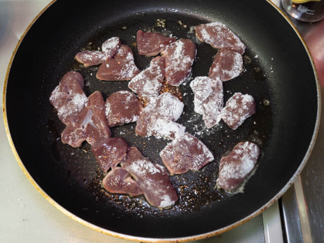 フライパンにごま油を熱して、片栗粉をまぶした豚レバーを並べた写真