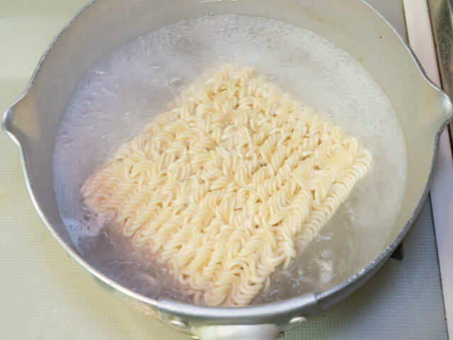鍋にお湯を沸かしてインスタント麺を入れた写真