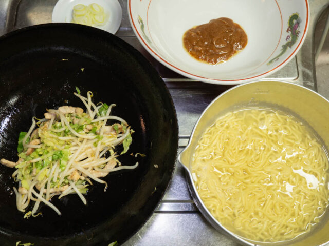茹でたインスタント麺の鍋、野菜炒めの中華鍋、液体スープを入れた丼の写真