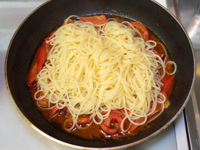 茹で上がったパスタをソースのフライパンに合わせた写真