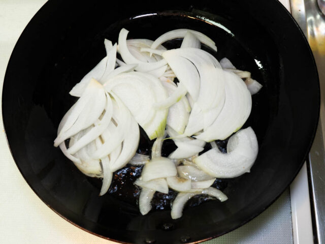 フライパンにごま油を熱して、玉ねぎを加えた写真