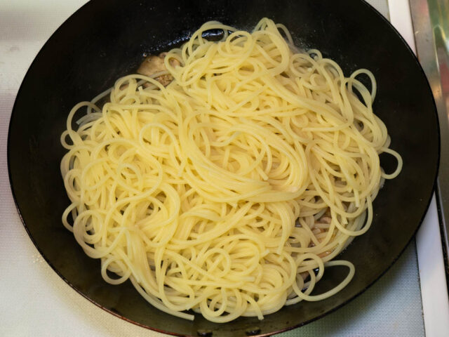 茹で上がったパスタをソースのフライパンに合わせた写真