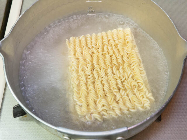 鍋にお湯を沸かしてインスタント麺を入れた写真