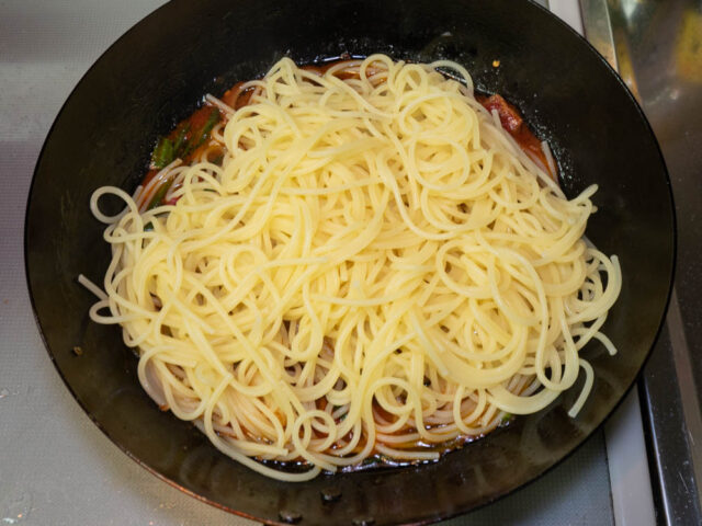 茹で上がったパスタをソースのフライパンに合わせた写真