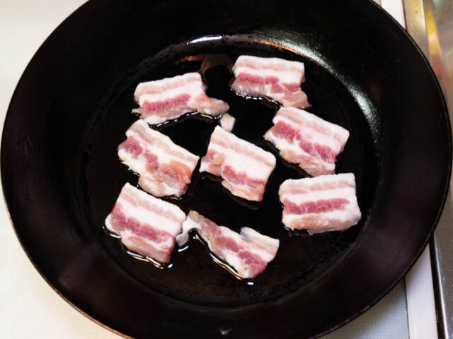 フライパンにサラダ油を熱して、塩豚を並べた写真