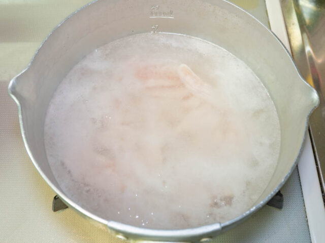 鍋にお湯を沸かして、小麦粉をまぶした鶏胸肉を茹でる写真