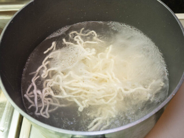 鍋にお湯を沸かして生麺を茹でる写真