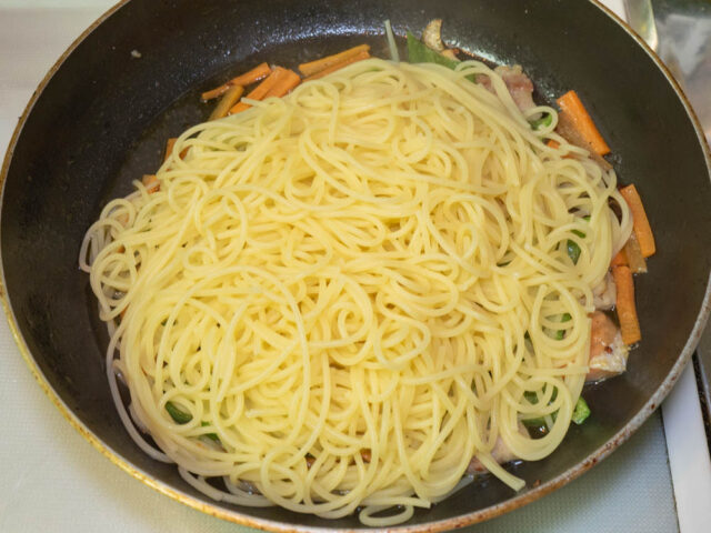 茹で上がったパスタをソースのフライパンに合わせた写真