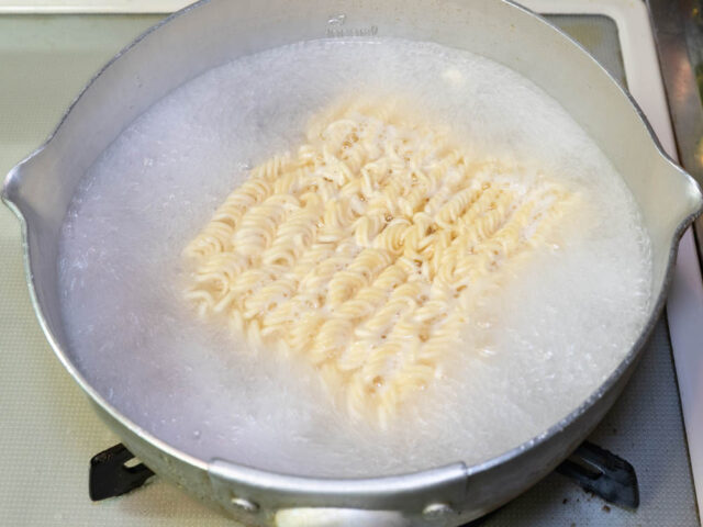 鍋にお湯を沸かしてインスタント麺を入れた写真