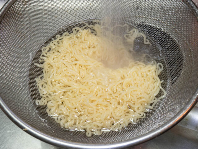 茹でたインスタント麺を流水でしめる写真