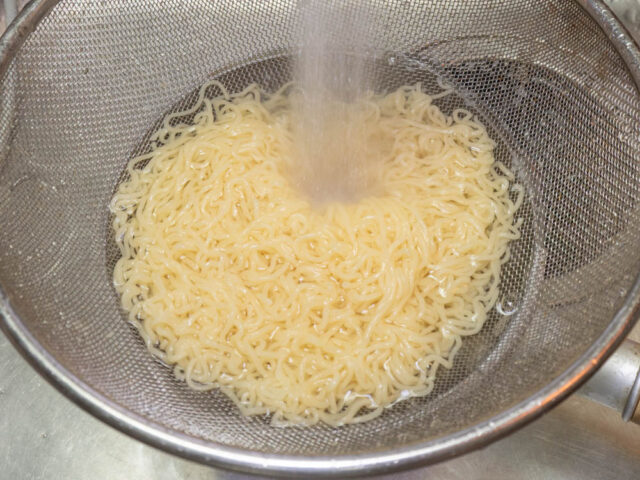 茹でた麺を流水で冷やす写真