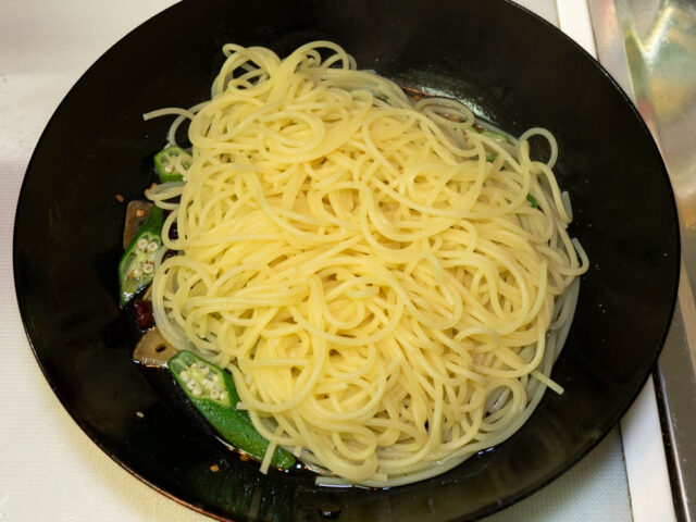 茹で上がったパスタをソースのフライパンに合わせた写真