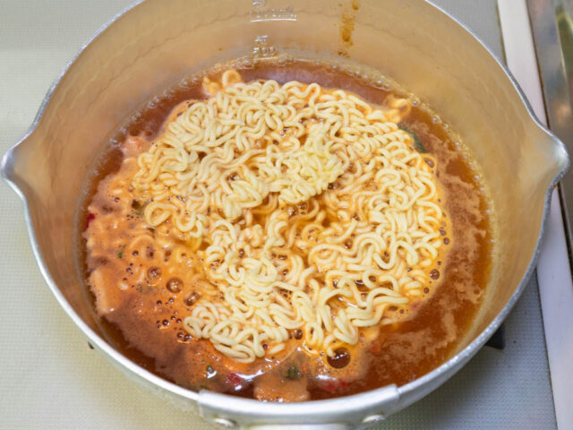 鍋にお湯を沸かして、粉末スープ、かやく、麺を入れた写真