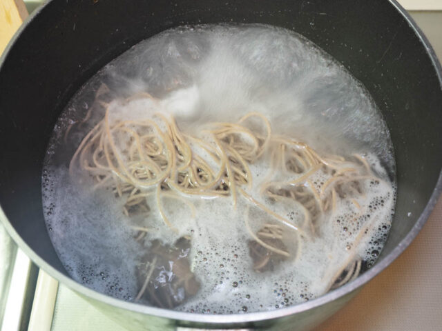 鍋にお湯を沸かして蕎麦を茹でる写真