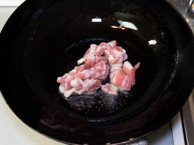 中華鍋にサラダ油を熱して豚バラ肉を入れた写真
