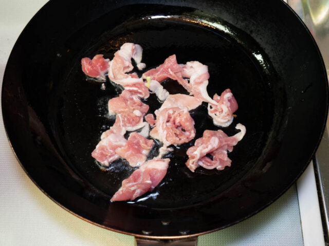フライパンにサラダ油を熱して、豚肉を炒める写真