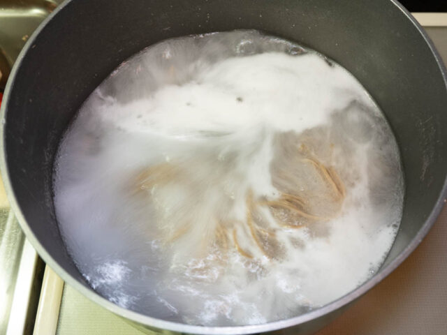 鍋にお湯を沸かし、蕎麦を茹でている写真