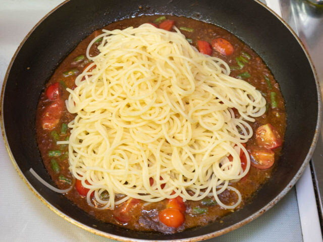 ソースのフライパンに茹で上がったパスタを合わせた写真