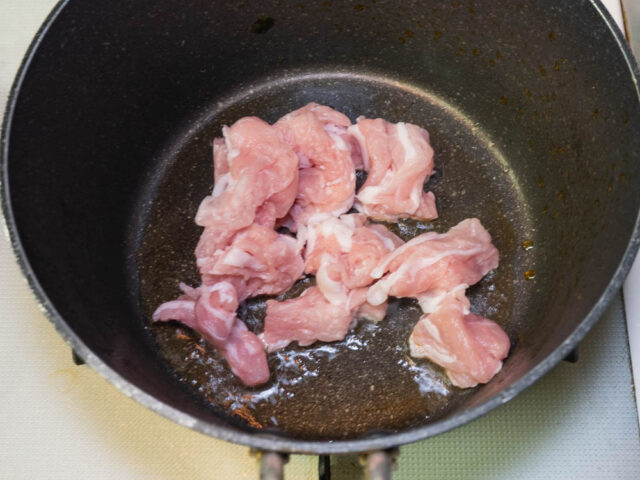 鍋に胡麻油を熱して豚肉を炒める写真