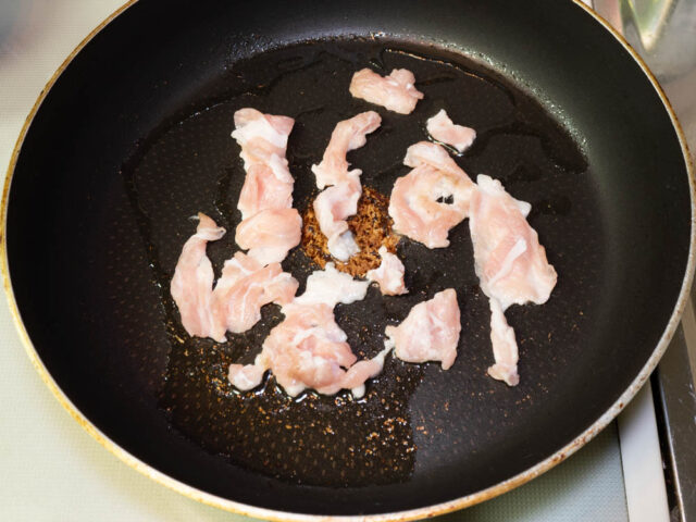 フライパンにサラダ油を熱して、豚肉を入れた写真