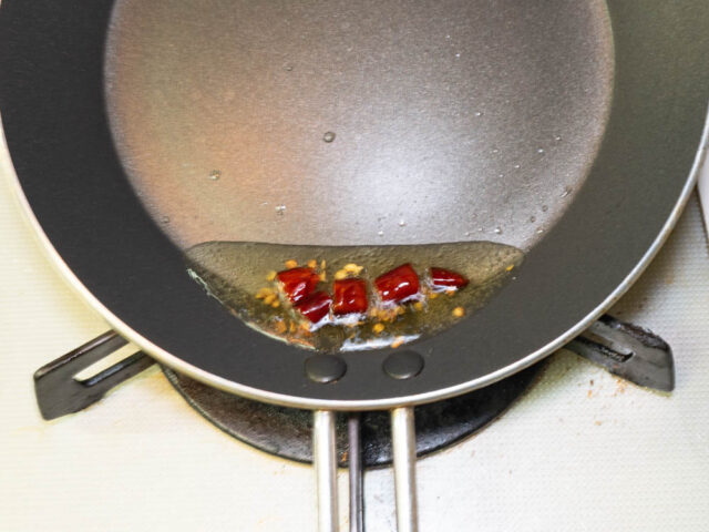 フライパンにサラダ油を熱して、唐辛子を入れた写真