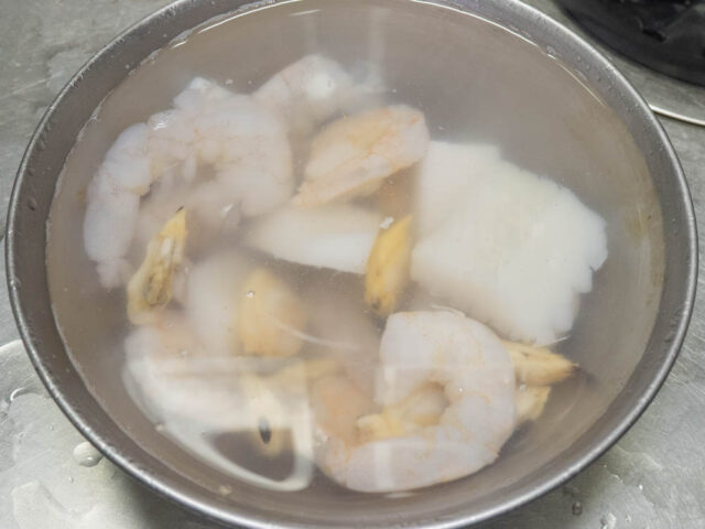 ボウルに冷凍のシーフードミックスと塩水を入れて解凍する写真