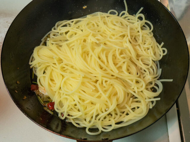 茹で上がったパスタをソースのフライパンに合わせた写真