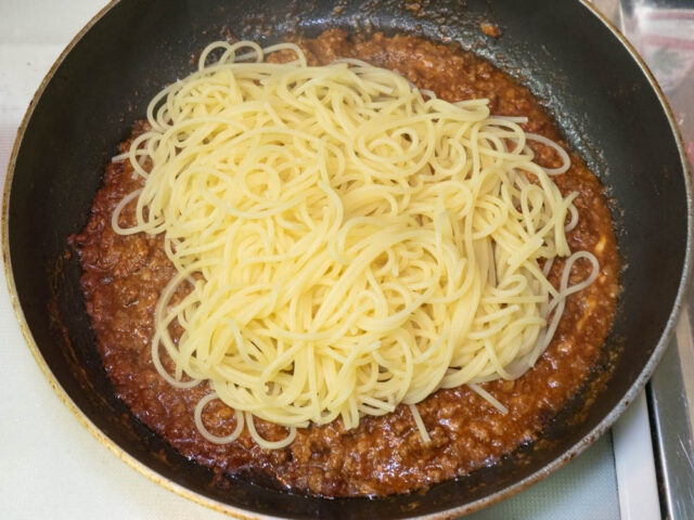 茹で上がったパスタをソースのフライパンに合わせた写真