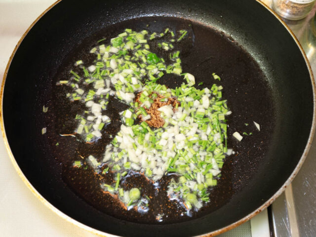 サラダ油を熱して、ニンニクとパクチーの茎を炒める写真